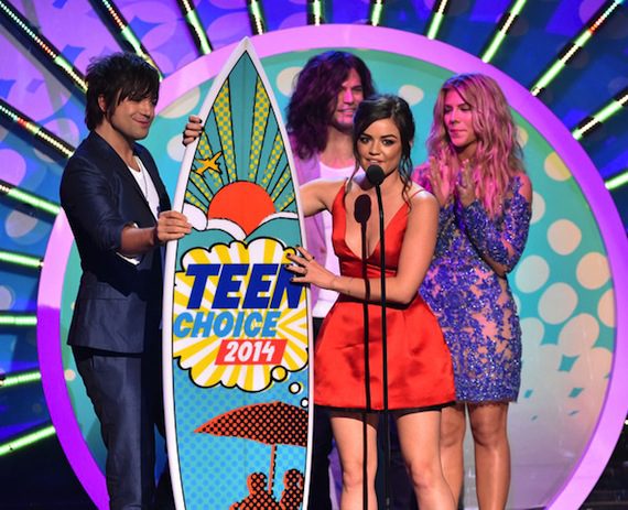 Lucy Hale accepts a surfboard from The Band Perry, who presented and performed on the show.