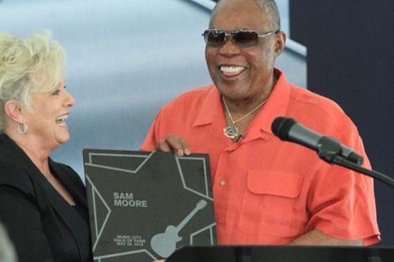 Country Music Hall of Famer Connie Smith (L) presents Sam Moore with commemorative plaque on stage.