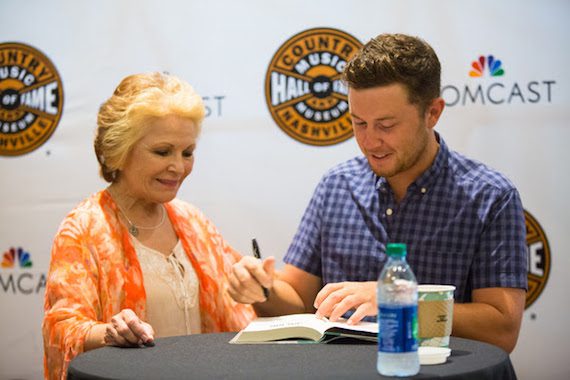 Scotty McCreery autographs a copy of his newbook Go Big or Go Home: The Journey Toward the Dream for a fan at theCountry Music Hall of Fame and Museum